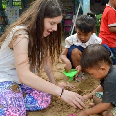 As part of her Projects Abroad service learning project in Cambodia for middle school students, a volunteer plays with a young child at a kindergarten. Part of the Experiential Learning model in Cambodia for middle school students, is for students to help at a kindergarten.